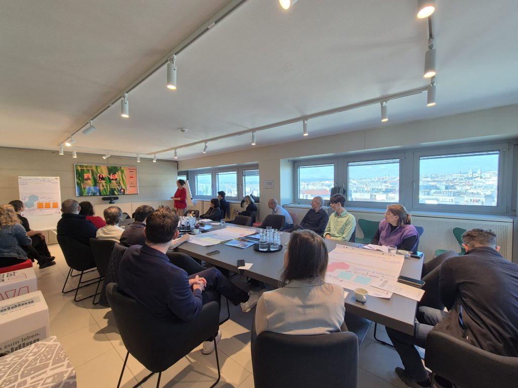 Ein Konferenztisch mit Ringsrum Menschen dran, eine Frau hält einen Experten Vortrag zu Satellitendaten